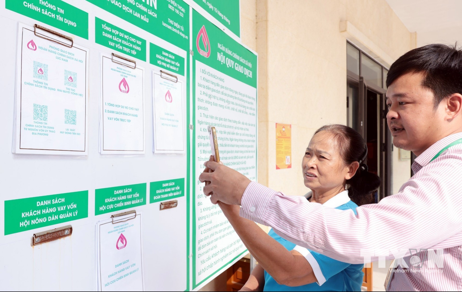 Cán bộ NHCSXH Lục Nam hướng dẫn Tổ trưởng tổ tiết kiệm tra cứu các chương trình vay vốn trên ứng dụng VBSP SmartBanking. (Ảnh: Trần Việt/TTXVN)
